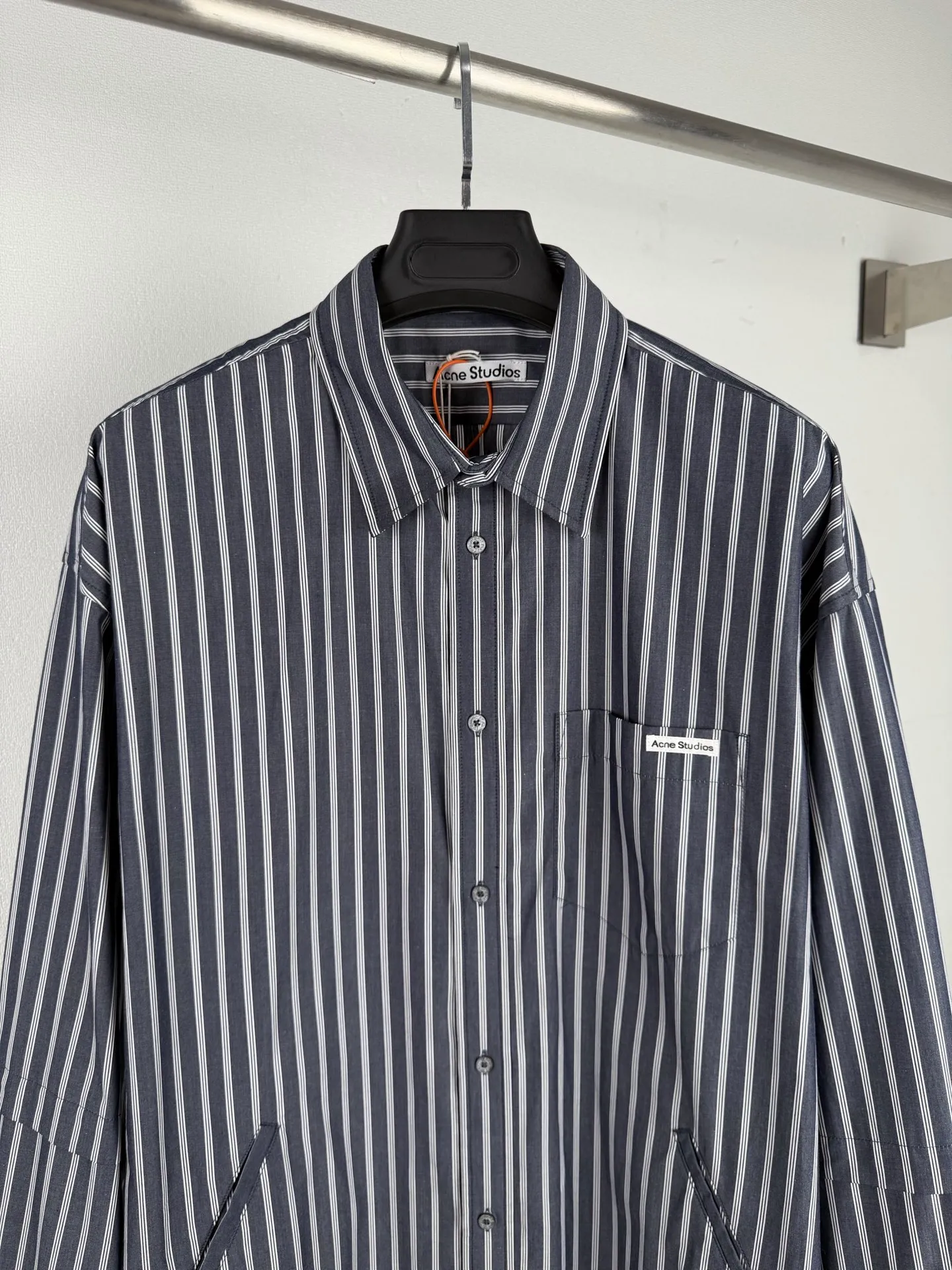 ACNE Studios logo double-sleeved striped long-sleeved shirt jacket. Customized matte rough weave combed poplin. Stiff and stylish. Comfortable and close to the skin. Mist charcoal blue interwoven with pure white vertical lines. The rise and fall of the lines reveal the cool and relaxed style of Scandinavia. Cleverly crafted layered double-sleeved deconstructed tailoring breaks the inherent paradigm of traditional shirts and gives the body three-dimensional layers. The season's iconic stripes are laid out vertically. Rhythm runs through the entire garment. The left breast pocket is embellished with the Acne Studios logo. The brand context is engraved restrainedly in the square inches. The side seams are equipped with wide welt pockets. It integrates styling aesthetics and practical functions. It adheres to the high-end aesthetics of minimalism and brings avant-garde ingenuity to daily life. It interprets the Nordic ready-to-wear attitude of symbiosis of relaxation and sophistication. Process 1: Infrared positioning cutting bed uses infrared emitters and infrared receivers to achieve precise positioning of materials. The accuracy can reach the micron level, thereby meeting the effect of high-precision cutting of plaid alignment. Process 2: Manual infrared line-drawing pockets are assisted by infrared technology to achieve precise positioning and marking of pocket positions, which retains the finesse and flexibility of hand sewing. Process 3: Using side-turning and embedded stitching technology, which can provide high-quality stitching results, smooth and tidy. Process 4: The fabrics have been sand-washed, have a better hand feel, are not easy to deform, are not easy to shrink, are not easy to fade, and maintain long-term beauty. Accessories: Customized 1:1 Acne buttons Customized 1:1 Acne Logo Customized 1:1 Acne Logo Fit: Loose Fit Size: 44 46 48 50